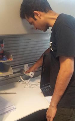 ADSC researcher Varun Krishna installs a power meter at a workspace in the ADSC offices to monitor its total energy consumption.